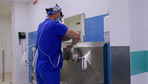 Side view of a doctor wearing device glasses in preoperational room. Surgeon washing hands carefully for neurosurgery. photo