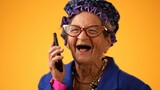 Closeup of funny crazy happy elderly old toothless woman talking on mobile cell phone wearing glasses isolated on solid yellow background studio portrait. 