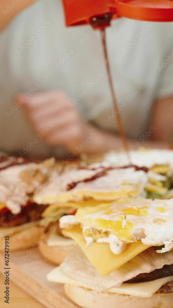 Vertical video. A Woman Pours Ketchup on the Eggs in the Burgers. Homemade Food. Warm Light in the Room. Slow Motion. Vertical video. A Woman Pours Ketchup on the Eggs in the Burgers. Homemade Food. Warm Light in the Room. Slow Motion.