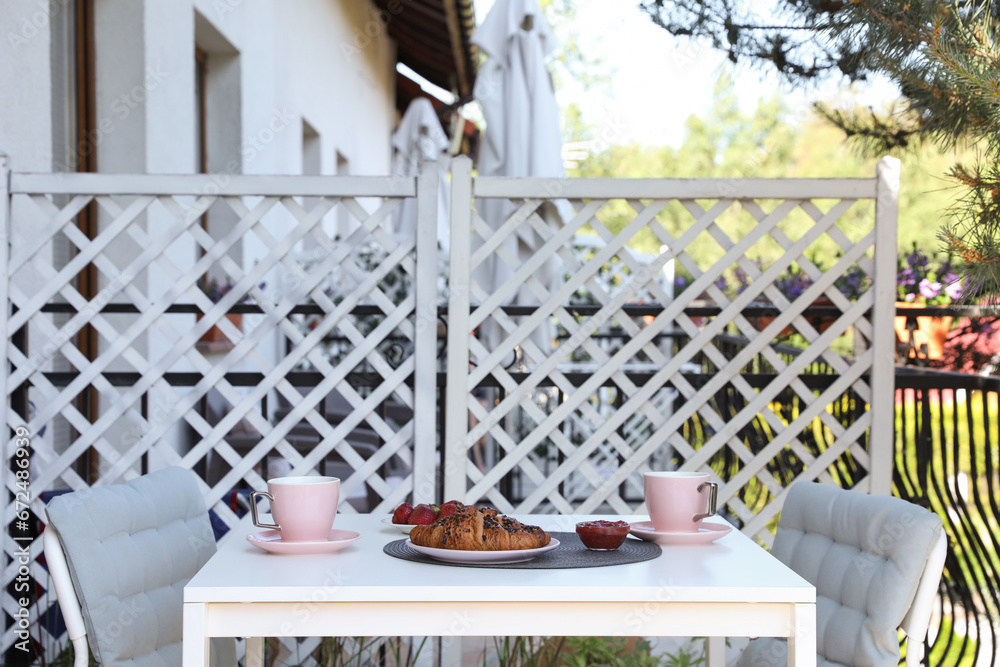 Obraz premium Outdoor breakfast with tea and croissants on white table on terrace