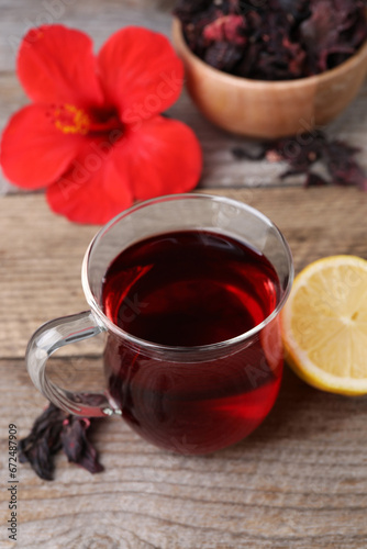 Cup of delicious hibiscus tea and lemon on wooden table
