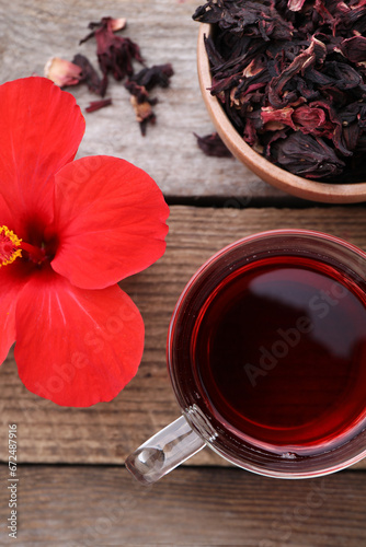 Delicious hibiscus tea and flowers on wooden table, flat lay