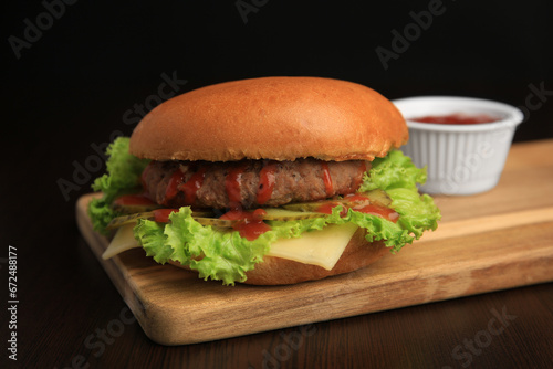 Tasty burger with patty, lettuce and cheese on wooden table, closeup