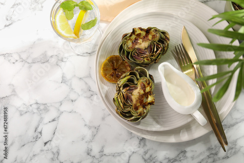 Tasty grilled artichokes served on white marble table, flat lay. Space for text