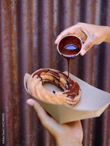 Pouring hot chocolate over donut churro photo