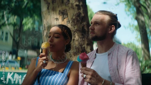 Young man and a woman on a date eating ice cream on a bench