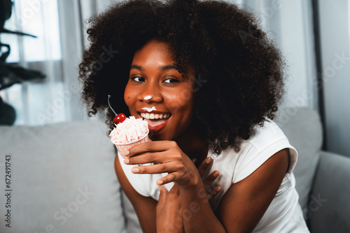 Funny beautiful young African blogger on mess face presenting cupcake in concept special cuisine. Content creating of social media online with favorite tasty sweets bakery dish. Tastemaker.