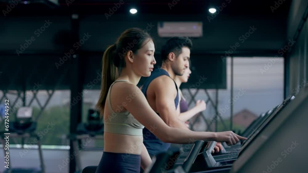 Fit young woman and man running on a treadmill during a workout class at fitness gym Fit young woman and man running on a treadmill during a workout class at fitness gym