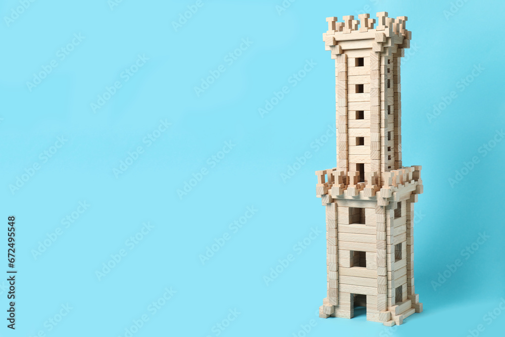 Wooden tower on light blue background, space for text. Children's toy