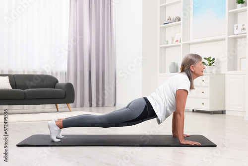 Senior woman practicing yoga on mat at home