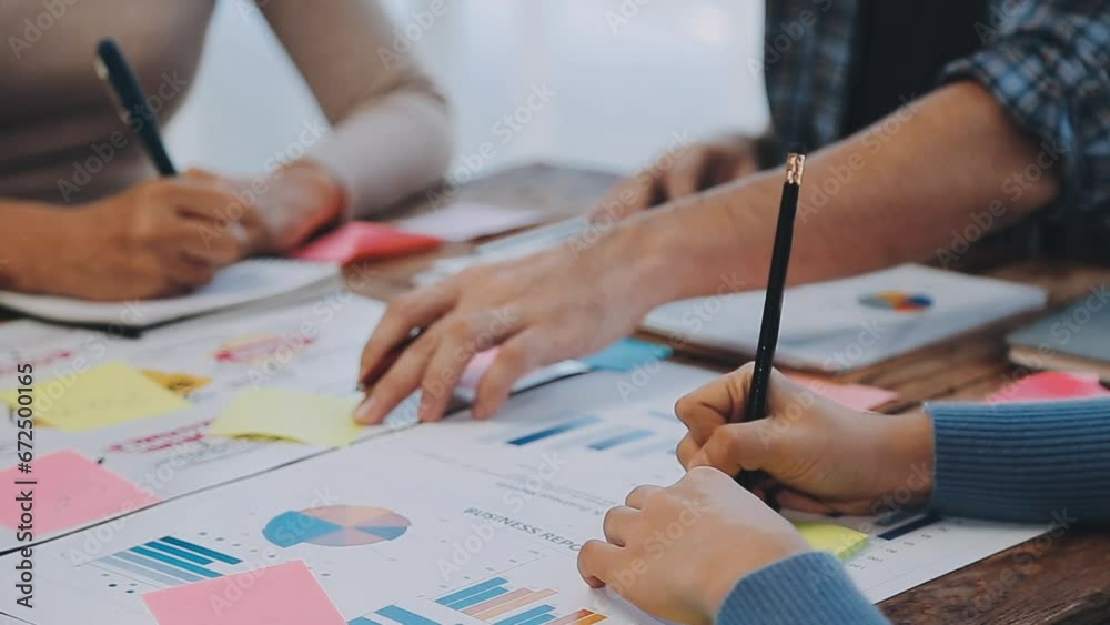 Two creative business people meeting and planning use post it notes sticky note on desk to share idea, Analysis data chart and graph with teamwork strategy brainstorming in office.