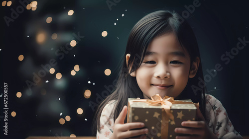 Pretty little Asian children girl smile with Christmas gift box with blurred bokeh background.