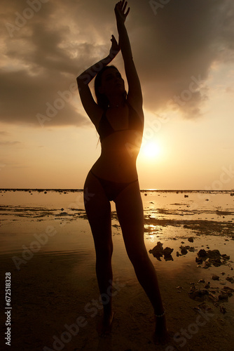 silhouette of girl on the beach at sunset. young beautiful woman and sea