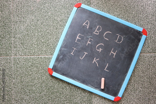 Slate with Letters ABC and colorful chalk, flat lay