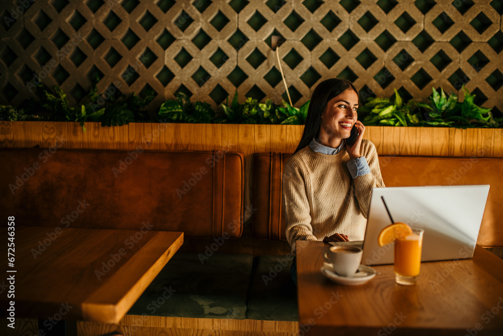 Young woman multitasking with laptop, phone, and orange juice and coffee. copy space