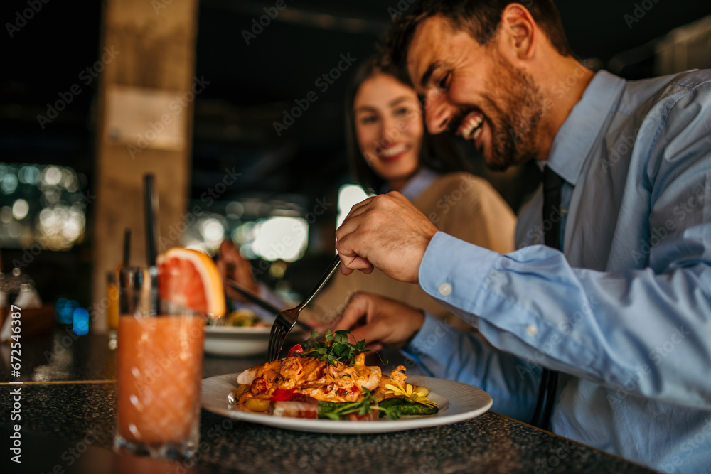 An interracial pair of friends bonding over a delectable lunch at a cozy cafe, their laughter echoing through the air as they delight in each other's company