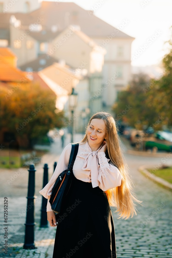 A young woman walks through the morning autumn sunny Prague