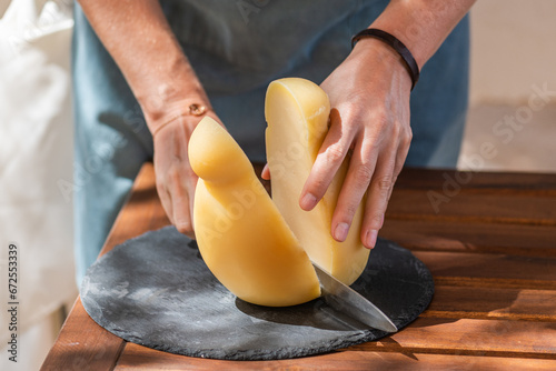 female hand's cutting a caciocavallo silano cheese on a cutting board photo