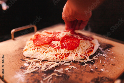 Man finalizing his home made pepperoni pizza