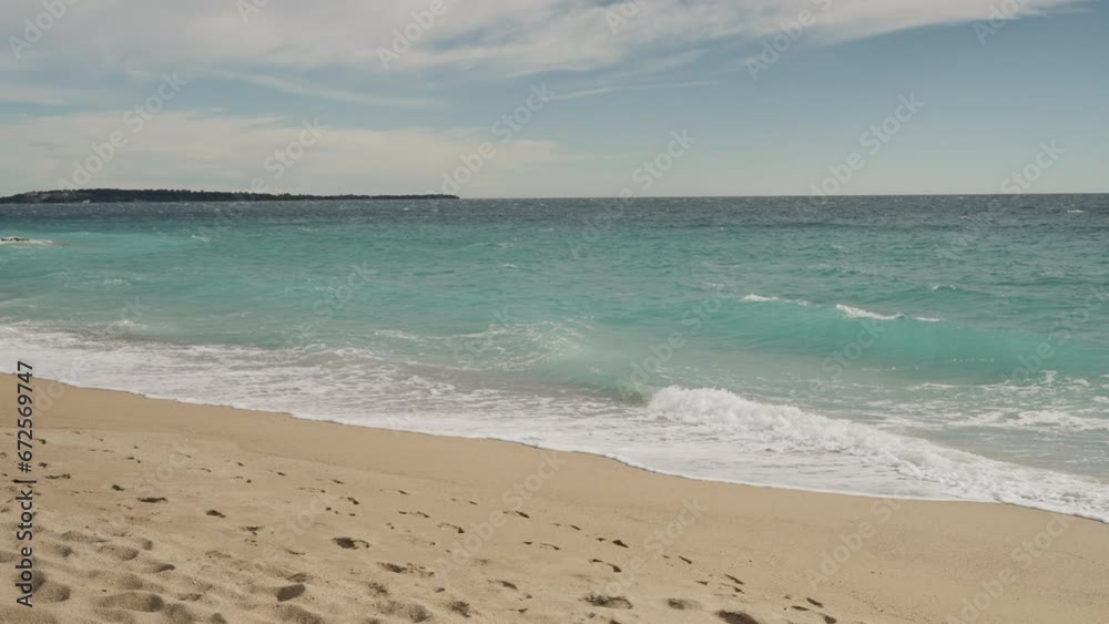 Slow motion clear blue waves with strong wind on a sandy empty beach in Cannes in spring