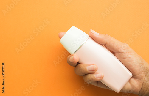 Bottle Cosmetic mockup Package Plastic Product Cream Tube Lotion Container Beauty Summer, hand woman holding Sunscreen Blank on Orange Background