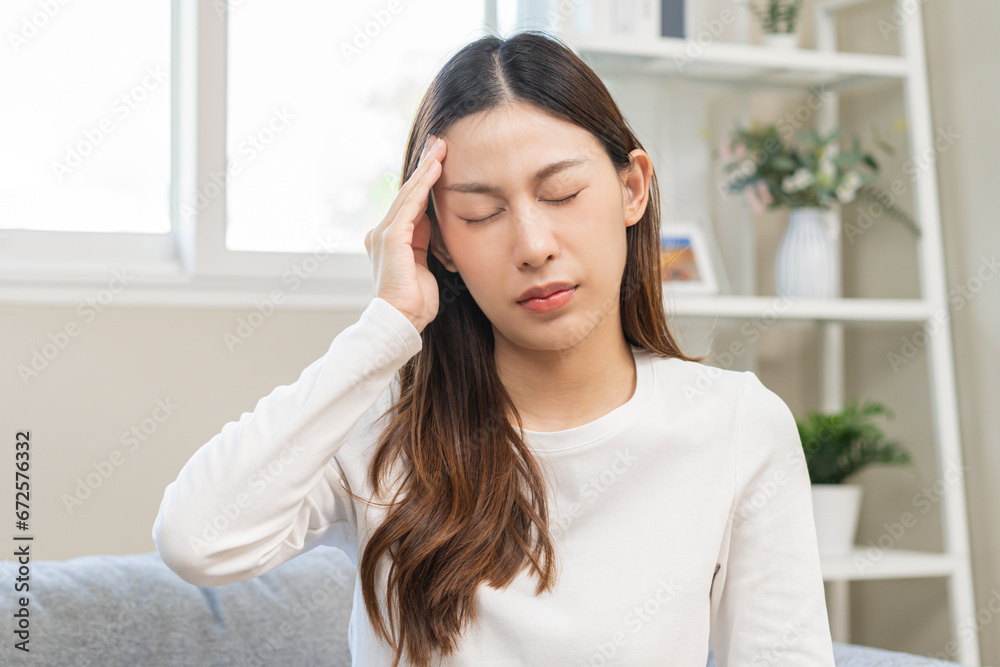 Dizzy asian young woman, girl headache or migraine pain suffering from vertigo while sitting on couch in living room at home, holding head with hand, health problem of brain or inner ear not balance. Dizzy asian young woman, girl headache or migraine pain suffering from vertigo while sitting on couch in living room at home, holding head with hand, health problem of brain or inner ear not balance.