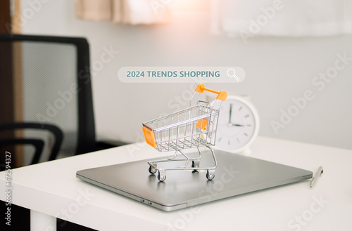 Trends 2024 concept with shopping trolley cart on table. E commerce, online shopping, finance, consumer economy and celebration concepts