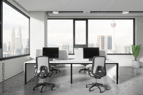 Light workplace interior with pc computers and table near panoramic window © ImageFlow