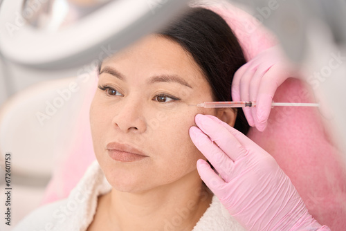 Asian woman receiving beauty injections in a cosmetology clinic