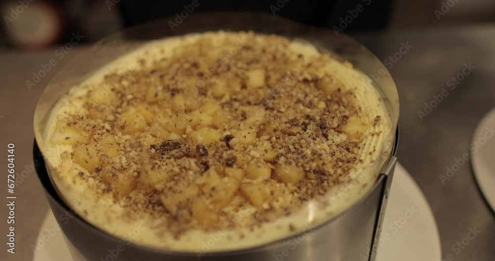 Sprinkling ground nuts on the cake during cooking. A professional confectioner prepares a cake with nuts, close-up. Sprinkling ground nuts on the cake during cooking. A professional confectioner prepares a cake with nuts, close-up.