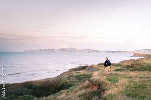 A man embracing a stunning sunrise sea view from the top of a cliff
