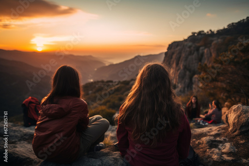 Young women watch the sunset on a mountain ledge campsite
