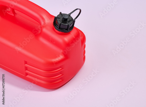 Red canister with engine oil or lubricant on a purple background. Idea of oil crisis. Copy space for text.