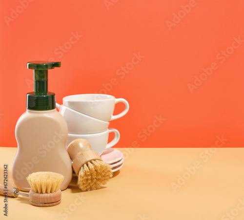 Set of clean kitchen ceramic tableware. Detergent dispenser and dishwashing brushes. Copy space for text.