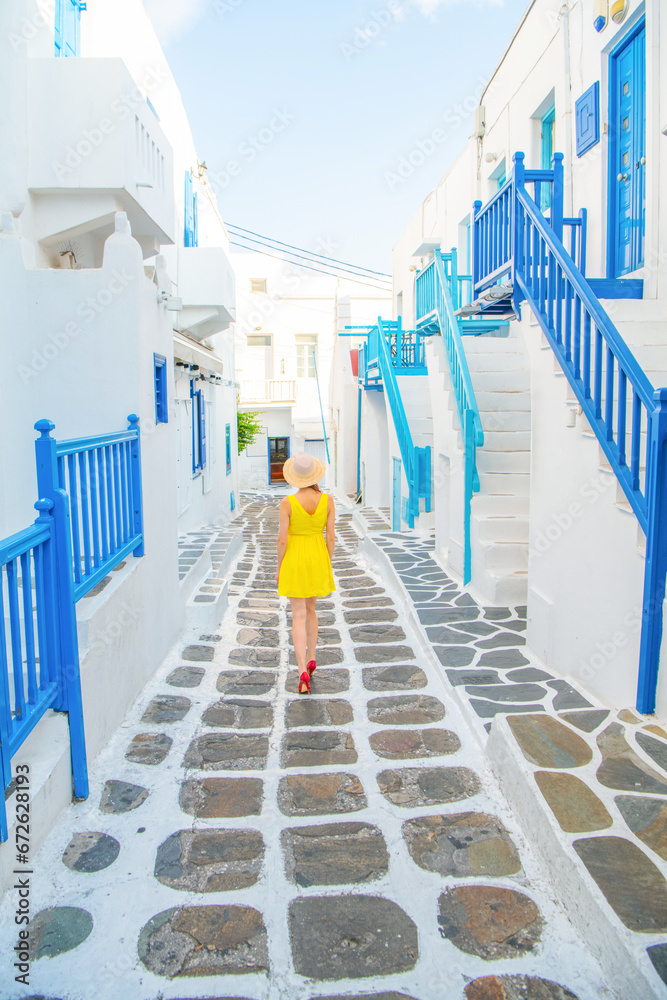 Obraz premium Woman in yellow dress at the Streets of old town Mykonos during a vacation in Greece, Little Venice Mykonos Greece