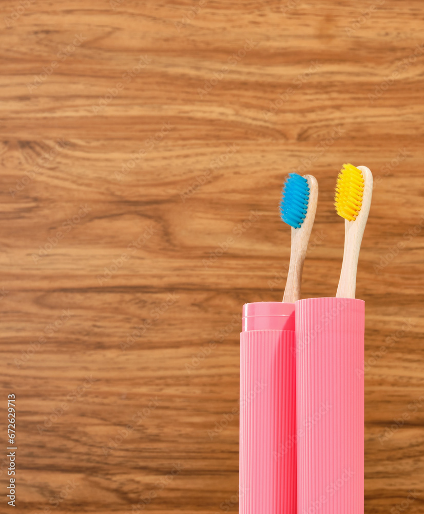 Classic bamboo toothbrushes in a pink container on a wooden background. Cleaning the teeth. Copy space for text. Classic bamboo toothbrushes in a pink container on a wooden background. Cleaning the teeth. Copy space for text.