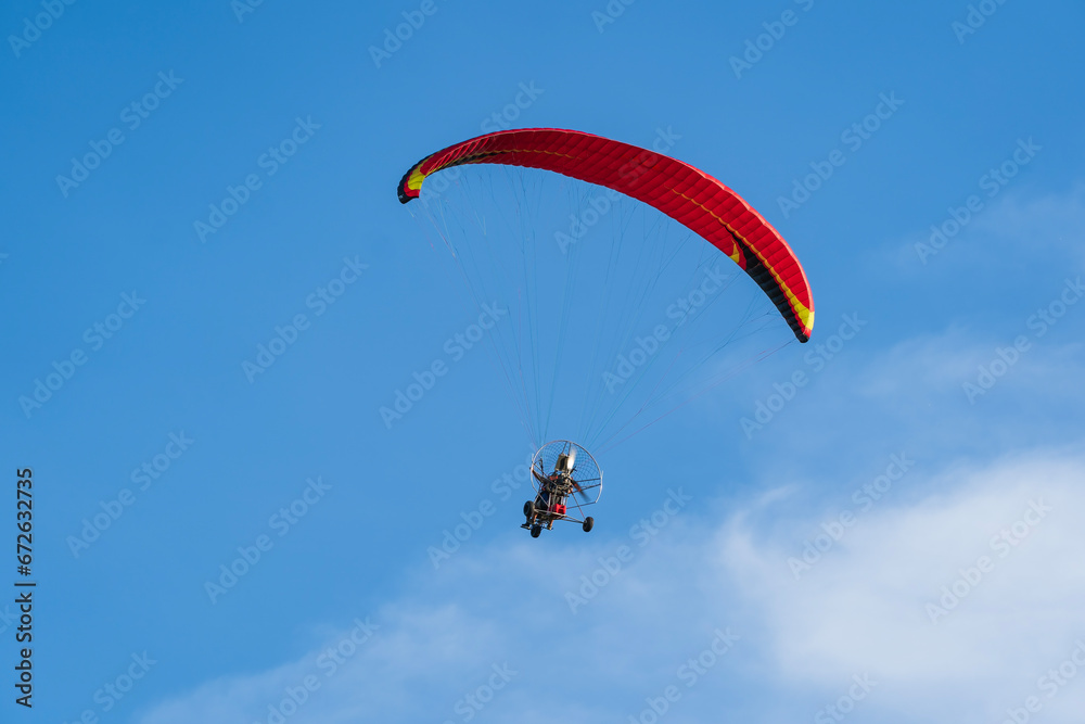 Flying with paramotor in the blue sky - Man riding paramotor in the blue sky background Flying with paramotor in the blue sky - Man riding paramotor in the blue sky background