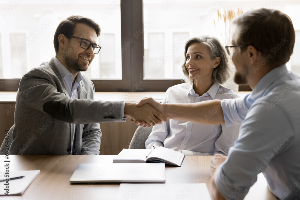 Team of business partners shaking hands after successful discussion, smiling, reaching agreement, giving greeting handshake over meeting table, working on partnership, cooperation Team of business partners shaking hands after successful discussion, smiling, reaching agreement, giving greeting handshake over meeting table, working on partnership, cooperation