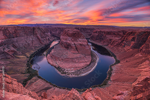 Sunset over Horseshoe Bend. View of the Colorado River valley in the evening with its reddish sandstone cliffs. Colorful clouds in the sky. Horseshoe shaped course of the river