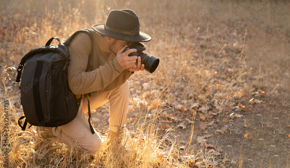 Fototapeta premium Young male nature photographer photography shoot in forest wild plants using a DSLR camera and zoom lens to create video and images