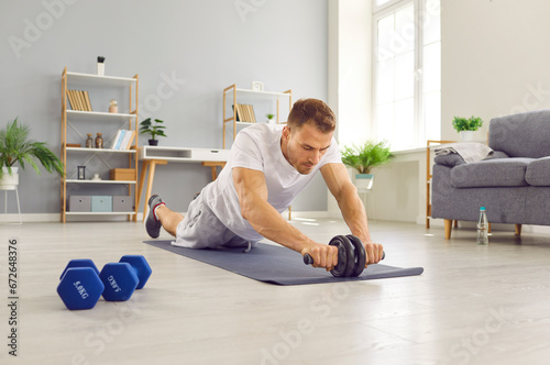 Portrait of a sporty athletic young man exercising at home on the floor. Young guy doing stretching exercises in the living room. Fitness, healthy lifestyle and home training concept.