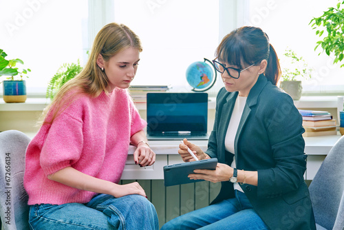 Counselor talking with teenage girl, using digital tablet for work photo