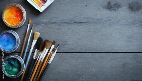 Art creative table background with watercolor paints palette paintbrushes pencils supplies tools on grey wooden desk, artist gray design blank workspace top view from above, flat lay, copy space 