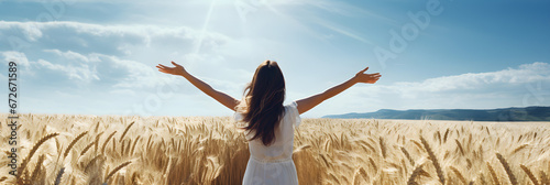 the woman with arms up is standing in a wheat field