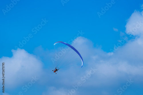 Flying with paramotor in the blue sky - Man riding paramotor in the blue sky background