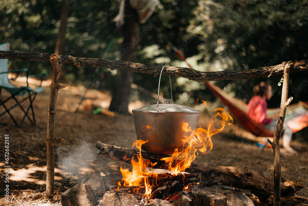 Travel a kettle over a fire burning on the river and sunset backgroun. Cooking over a campfire. Travel a kettle over a fire burning on the river and sunset backgroun. Cooking over a campfire.