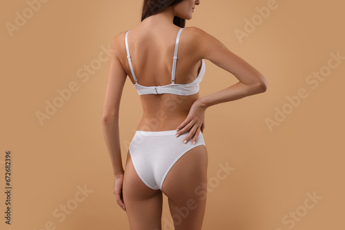 Young woman in stylish white bikini on beige background, closeup