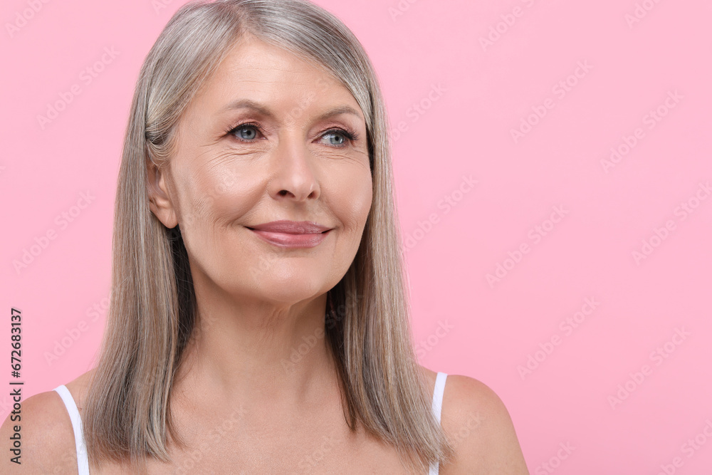 Portrait of beautiful senior woman on pink background. Space for text