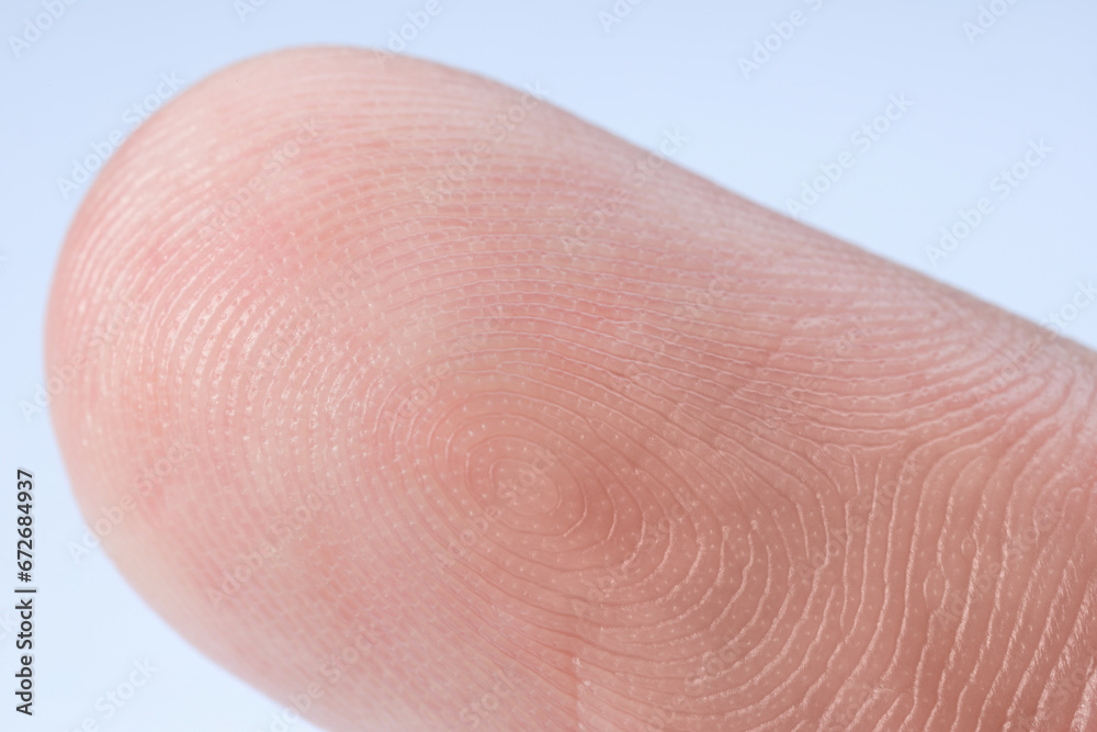 Fototapeta premium Finger with friction ridges on light blue background, macro view