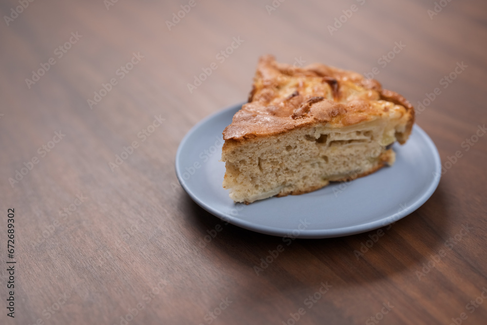 A piece of charlotte apple pie on a saucer on walnut table